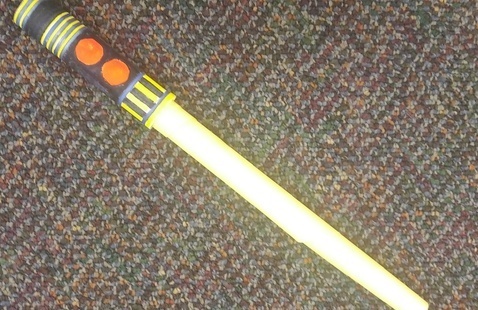 yellow paper lightsaber on mulicolor, dark background
