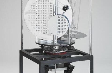 This black and white photograph shows a contemporary sculpture comprising several metal discs and rods of varying shapes.