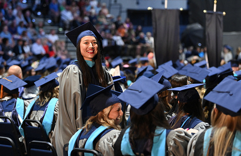 Graduating student standing up while rest of the graduating students remain sitting down