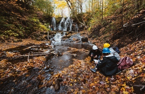 Students collecting samples near a waterfall.