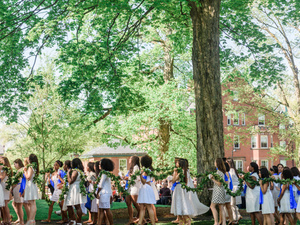 Graduating students in blue scarves carry laurel chain.