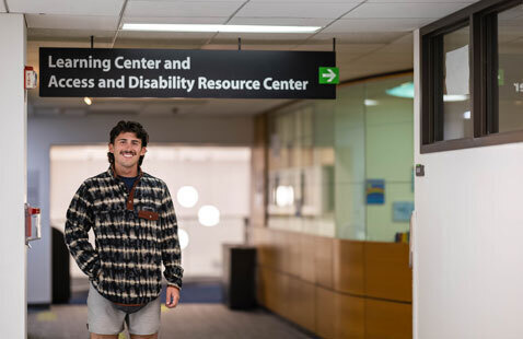 An image of a student in front of Oakton College's Access and Disability Resource Center on campus.
