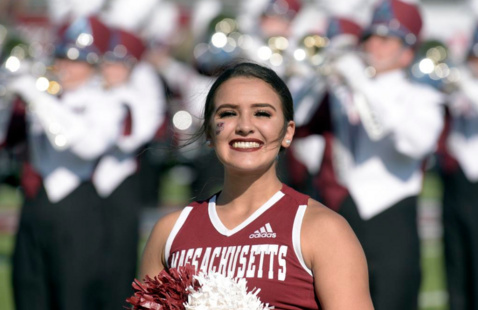 Cheerleader in front of UMass marching band