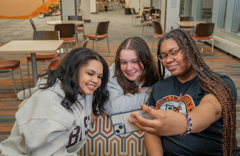 A group of students talking and hanging out with each other in a hallway.