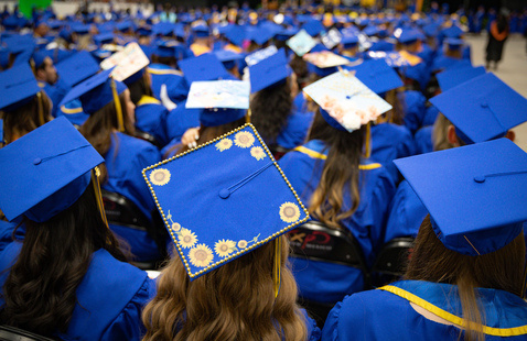 CNM graduates wearing caps, watching and listening to ceremony speakers. 
