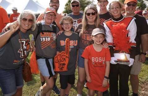 A group of people on family weekend wearing orange and celebrating the football team with foam fingers and bg spirit wear! 