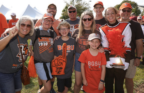 A group of people on family weekend wearing orange and celebrating the football team with foam fingers and bg spirit wear! 