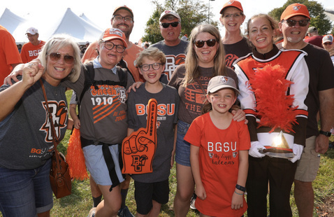 A group of people on family weekend wearing orange and celebrating the football team with foam fingers and bg spirit wear! 