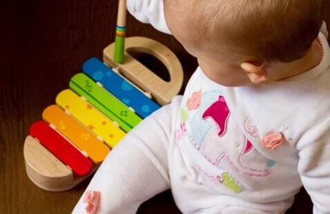 baby playing on a colorful xylophone