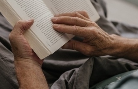 A pair of adult hands holds open a book to read