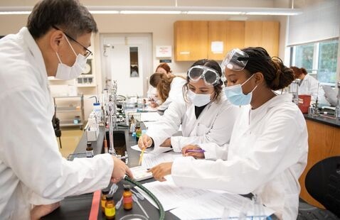 Three people in a lab wearing masks.