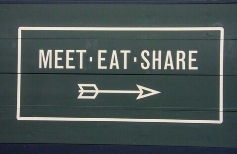A sign that says "Meet, Eat, Share" with an arrow.