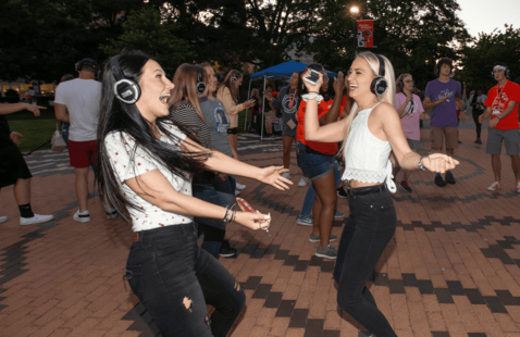 2 students dancing with headphones on at a silent disco event