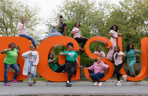 a photo of bgsu alumni posing around the BGSU letters during the day