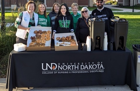 Staff and faculty from the CNPD pose with donuts and coffee behind a table with the UNDCNPD logo.