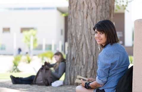 Female student smiling in front of large Cottonwood tree