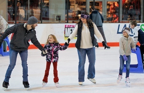A group of people ice skating in an indoor arena
