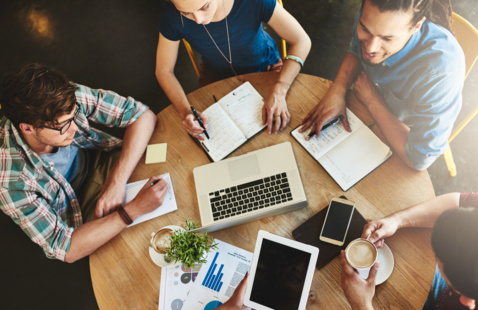 a group of students around a table figuring out a plan 