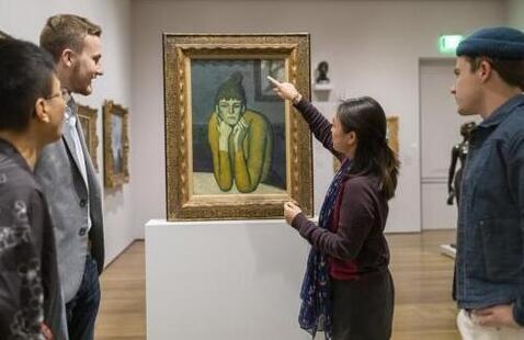 A young woman in a gallery of paintings and sculptures speaks to an audience.