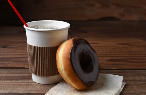 a coffee and a donut together on a wood table
