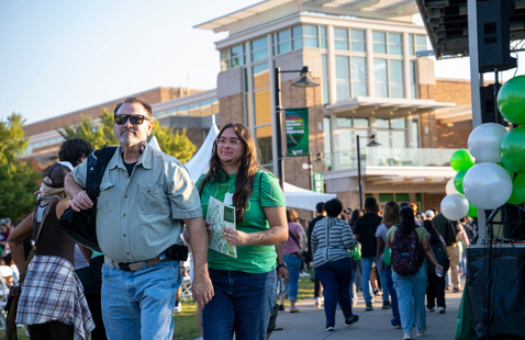 Photo of a student and parent walking in front of the University Union at UNT Preview Day.