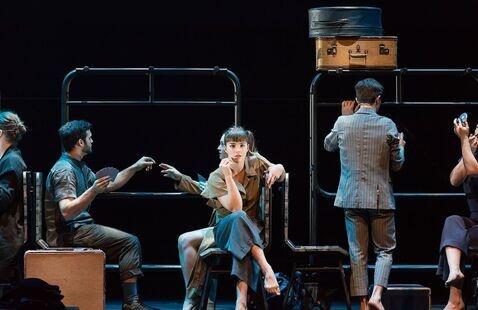 A young woman sits on train, surrounded by bustling passengers and baggage.
