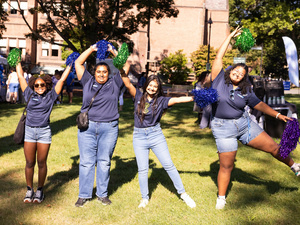 Orientation leaders pose in different cheer positions with poms.