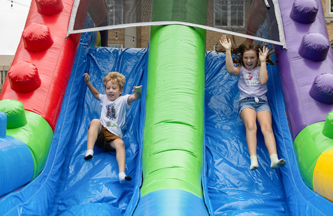 2 young kids playing outside on a sunny day on an inflatable