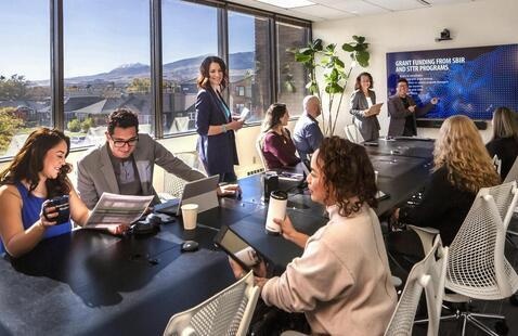 Students around a conference table discussing business with mountains in the background