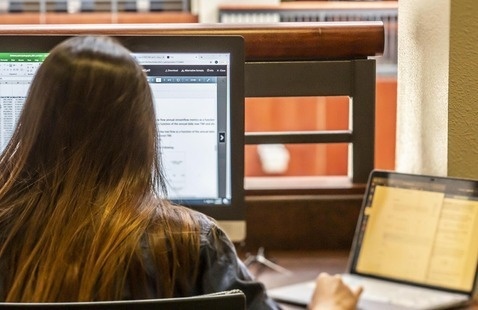 Student learning on a laptop and second monitor working on a spreadsheet