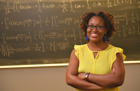 A student in front of a chalkboard with equations