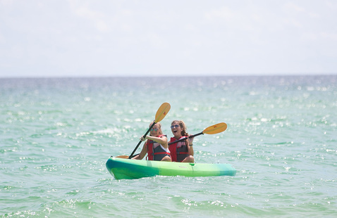 Two students kayaking in a kayak in a body of water.