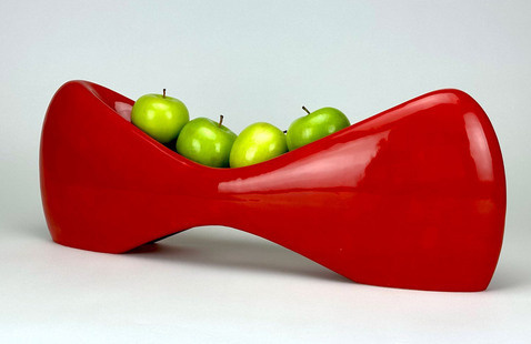 Red porcelain bowl holding green apples
