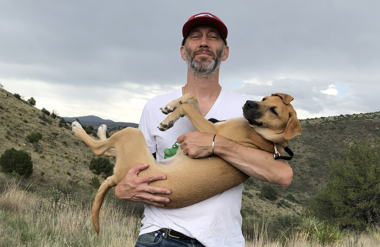 Photograph of Richard Maxwell holding a dog in his arms