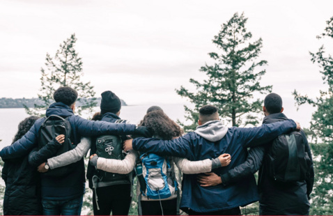Young people with backpacks, in group bonding on mountain top