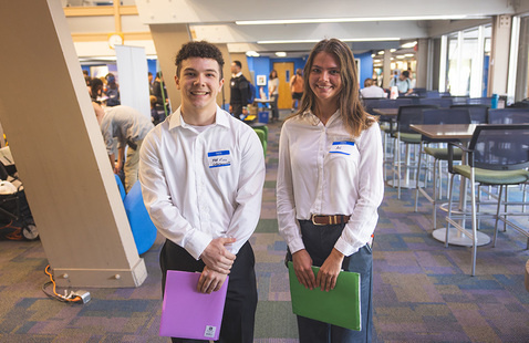 Two students smiling at the camera during a career fair event.