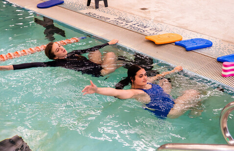 A swim instructor mentors a student on pushing off the wall in the Dixon Pool.