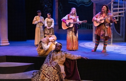 Students performing on stage with instruments and regal costumes