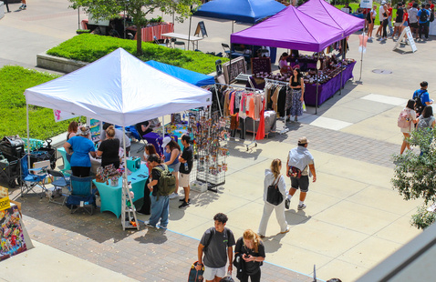 Bustling crowd walking on sidewalk visiting different tables