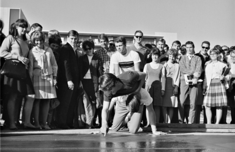 Group of students watching one student sign wet cement.