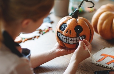 A girl paints a pumpkin.