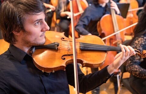 Students playing string instruments in an orchestra.