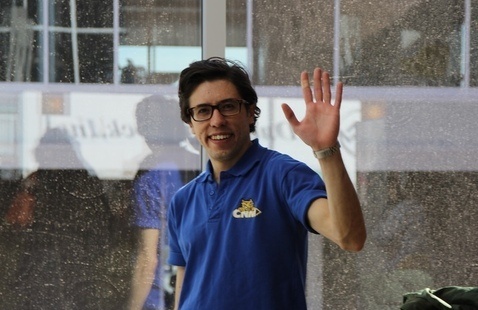 Male in CNM shirt waves and smiles at the camera