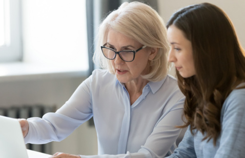 Two women looking at a laptop reviewing a project together