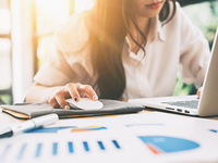 Person analyzing marketing data on a laptop with charts and graphs on the desk.