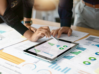 Team reviewing market research data and charts on a tablet and printed reports.