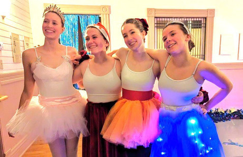 four female dancers in tutus of various colors
