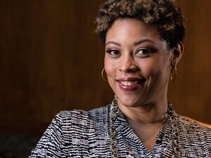 Shalanda Young smiles at the camera, her arm resting on a wooden table.