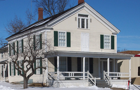 Photograph of a white house with snow.
