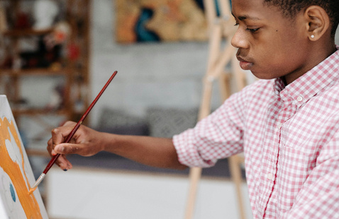A Boy Painting on a Canvas